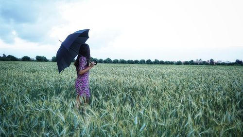 Woman standing in field with a parasol