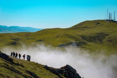 High angle view of people standing amidst fog on mountain