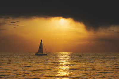 Sailboat sailing on sea against sky during sunset