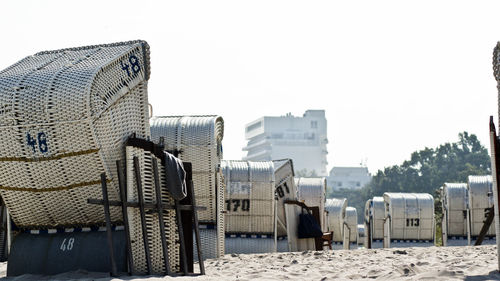 Hooded beach chairs on sandy beach against clear sky