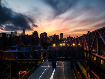 Illuminated bridge and buildings against sky during sunset