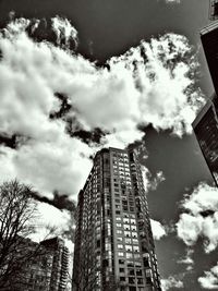 Low angle view of modern skyscraper against cloudy sky