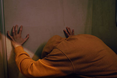 Rear view of woman hand on wall at home