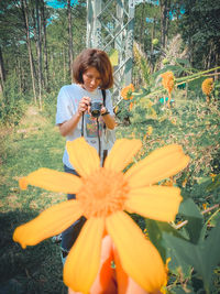 Woman holding umbrella while standing on field