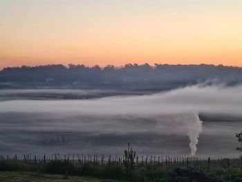 Smoke emitting from factory against sky during sunset