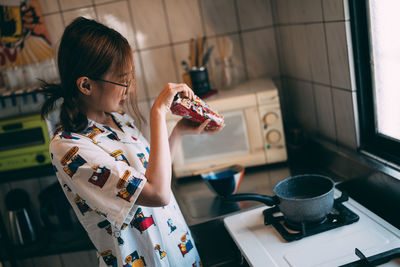 Side view of young woman drinking coffee at home