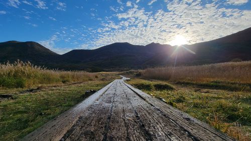 Empty road leading towards mountains against sky