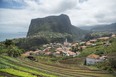 Scenic view of townscape by mountain against sky