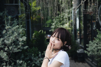 Portrait of young woman standing against trees