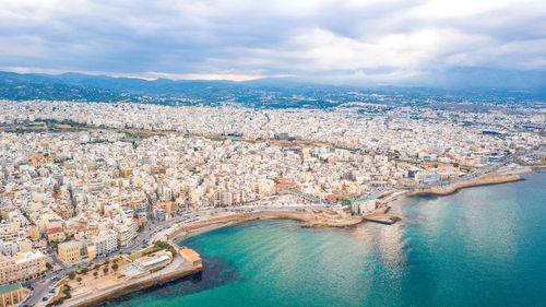 High angle view of townscape by sea against sky