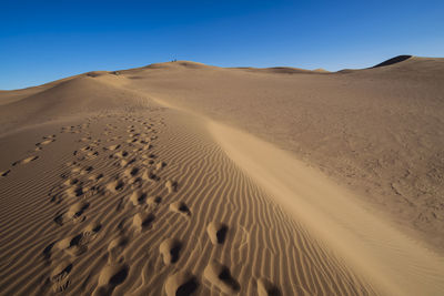 Scenic view of desert against clear blue sky