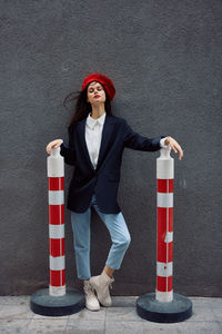 Portrait of young woman standing against wall