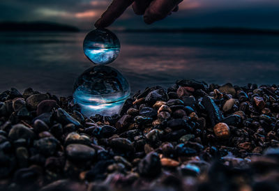 Close-up of crystal ball at beach during sunset