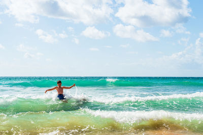 Boy with arms outstretched playing in sea, alvor, algarve, portugal, europe