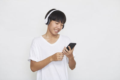 Young man using smart phone against white background