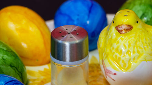 Small salt shaker next to a clay chick and colorful easter eggs