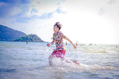 Man running in sea against sky