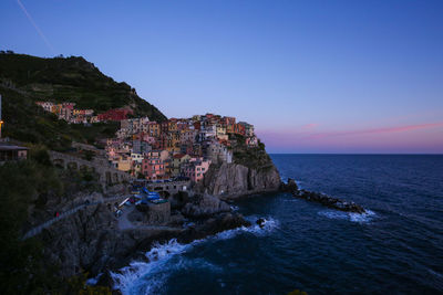 Manarola at sea shore against sky during dusk