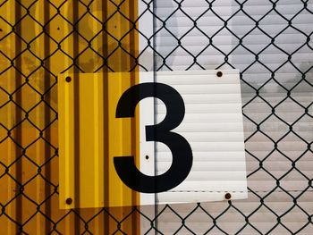 Close-up of number 3 on chainlink fence