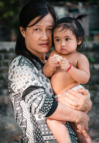 Portrait of mature woman holding granddaughter