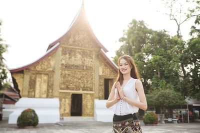 Portrait of young woman standing against building lao women 