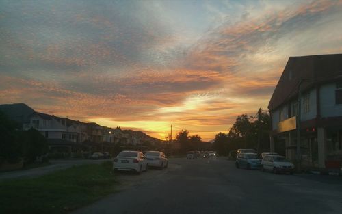 Cars on street against sky during sunset