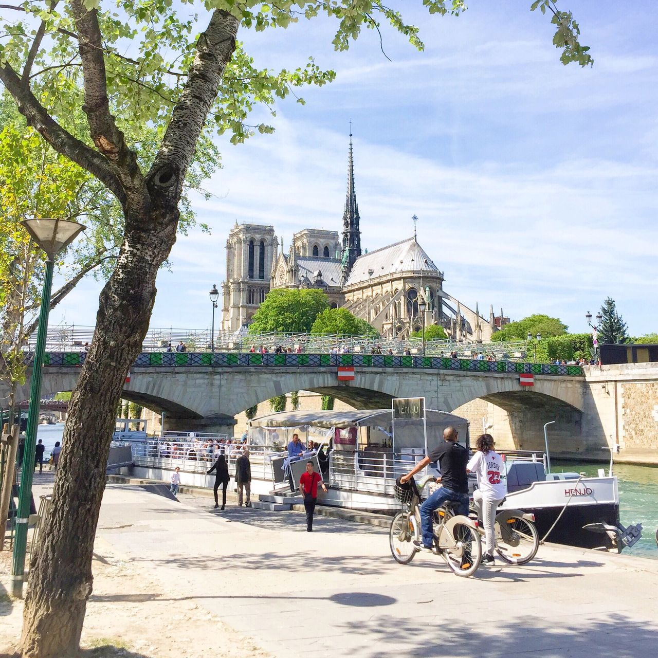 architecture, building exterior, built structure, men, tree, lifestyles, person, transportation, large group of people, leisure activity, city, sky, bicycle, mode of transport, walking, city life, mixed age range, land vehicle, travel