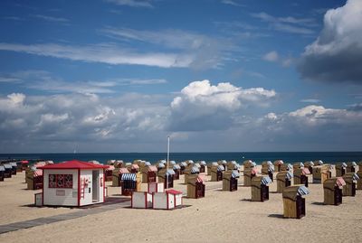 Hooded beach chairs on shore against sky