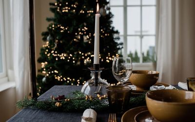 Lit candle on a festive decorated dinner table at christmas