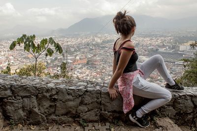 Rear view of woman against sea and cityscape