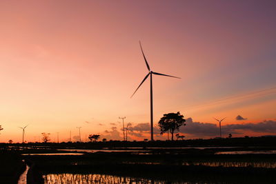 Silhouette windmill on field against sky during sunset