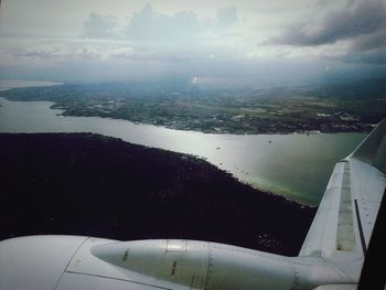 Airplane flying over landscape against sky