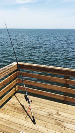 Fishing rod on wooden pier by sea