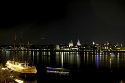 River by illuminated city against sky at night