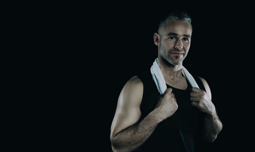 Portrait of mid adult man standing against black background