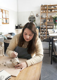 Artisan with ceramic working tool or pencil sketches on ceramic.