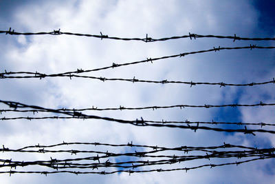 Low angle view of barbed wire against sky