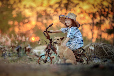 Cute girl with dog riding bicycle against trees