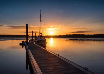 Pier on lake against sky during sunset