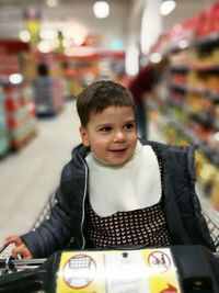 Boy sitting in shopping cart at supermarket