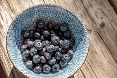 Organic blueberries in a blue and white bowl on the rustic wood background of an old farm table 