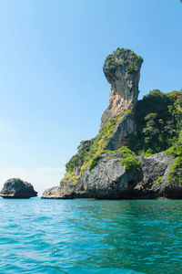 Rock formations in sea against clear blue sky