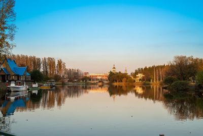 Reflection of trees and buildings in lake against sky