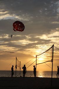 Silhouette people playing on beach against sky during sunset