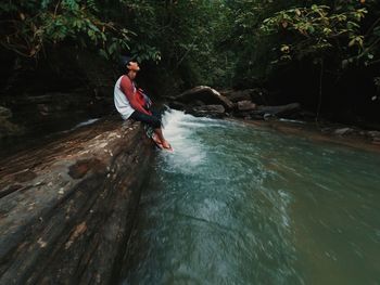 Man surfing in river against trees in forest