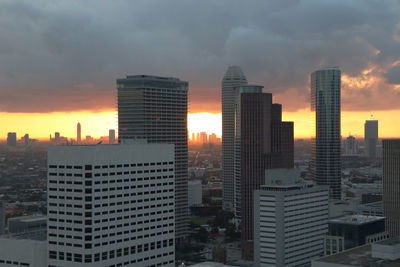 Modern buildings in city against sky during sunset