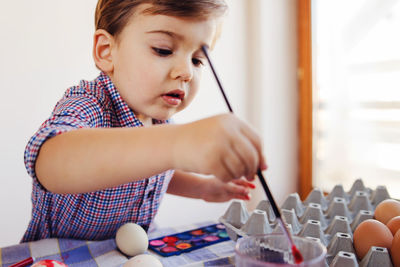 Cute boy painting eggs home