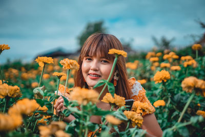 Portrait of girl with yellow flowers on field