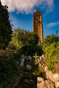 Low angle view of clock tower amidst trees and buildings against sky