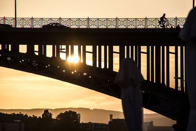Silhouette people on bridge against clear sky during sunset
